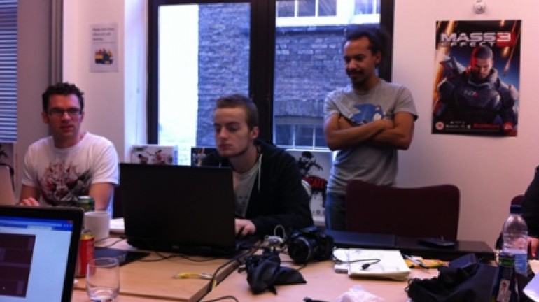Theo Chin, Luc Shelton, and Mark Backler looking suspiciously at a computer screen in a conference room at the UKIE offices in central London.